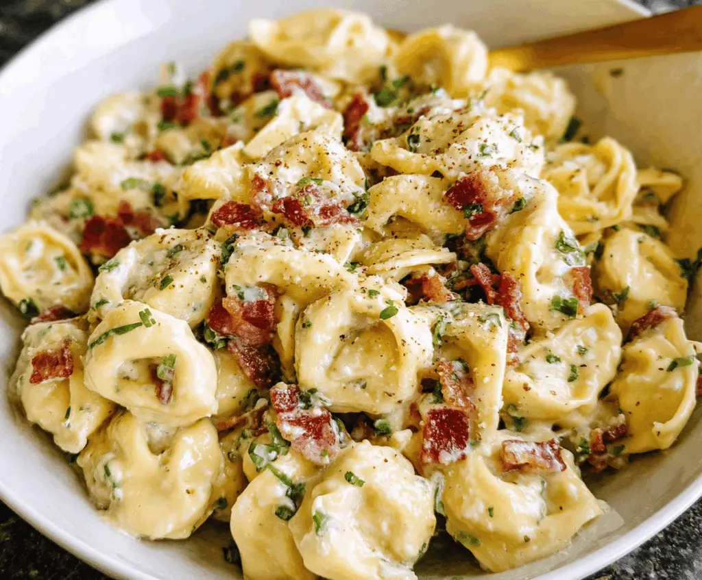 Creamy tortellini carbonara topped with grated Parmesan cheese and fresh parsley in a white bowl on a rustic wooden table