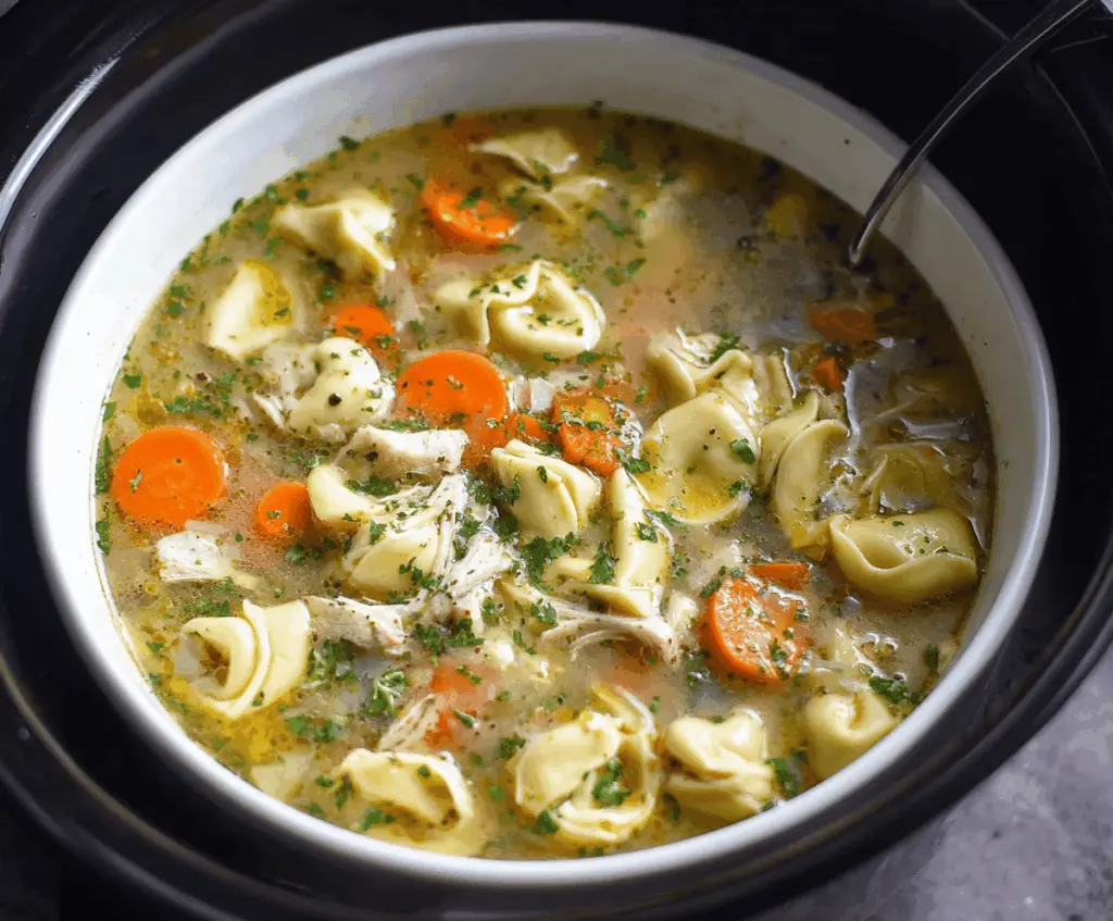 Creamy crockpot chicken tortellini soup with tender chicken, cheese tortellini, vegetables, and herbs in a flavorful broth