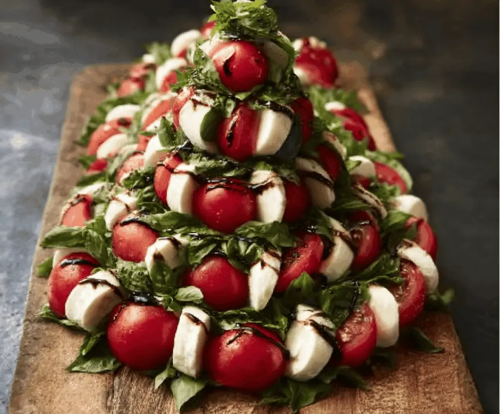 Festive Caprese Christmas Tree with cherry tomatoes, mozzarella, and basil for holiday appetizers.