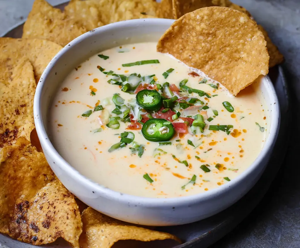 Creamy white queso dip served with tortilla chips, perfect for parties and snacks.
