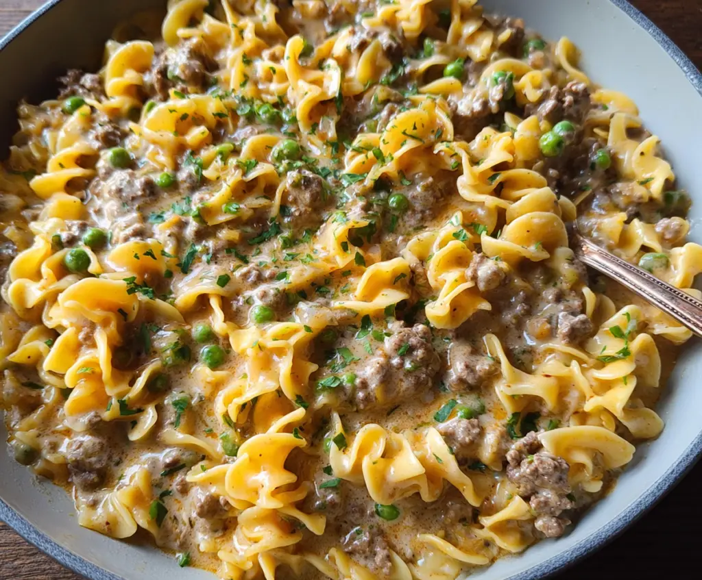 Creamy Ground Beef Stroganoff served over noodles with a sprinkle of fresh herbs.