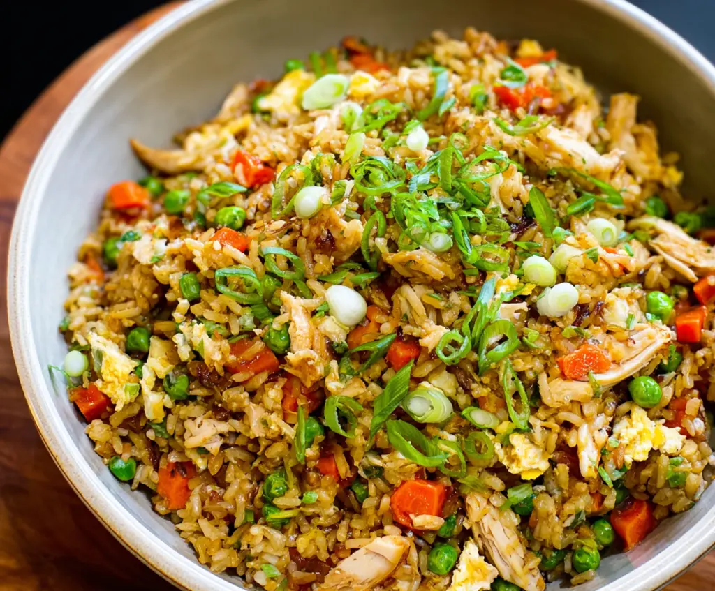 Delicious rotisserie chicken fried rice served in a bowl with vegetables and herbs